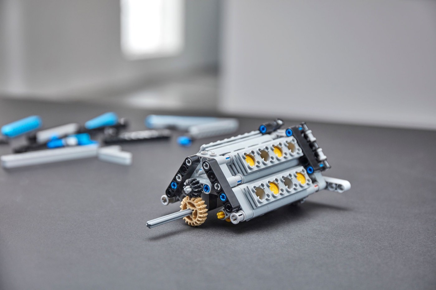The LEGO Technic W16 engine module from set 42083, built as two banks of cylinders with yellow pistons, sitting on a grey surface